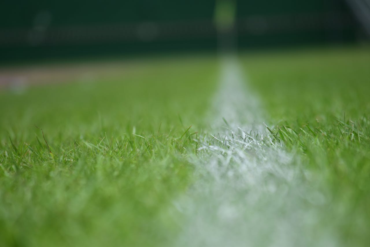 Blurred close-up of a soccer field's vibrant green grass with white line marking.