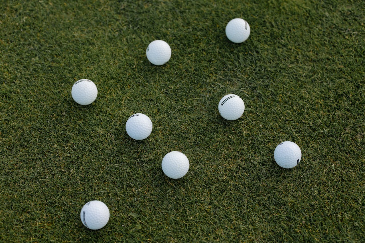 A visually appealing composition of scattered white golf balls on a lush green grass field.