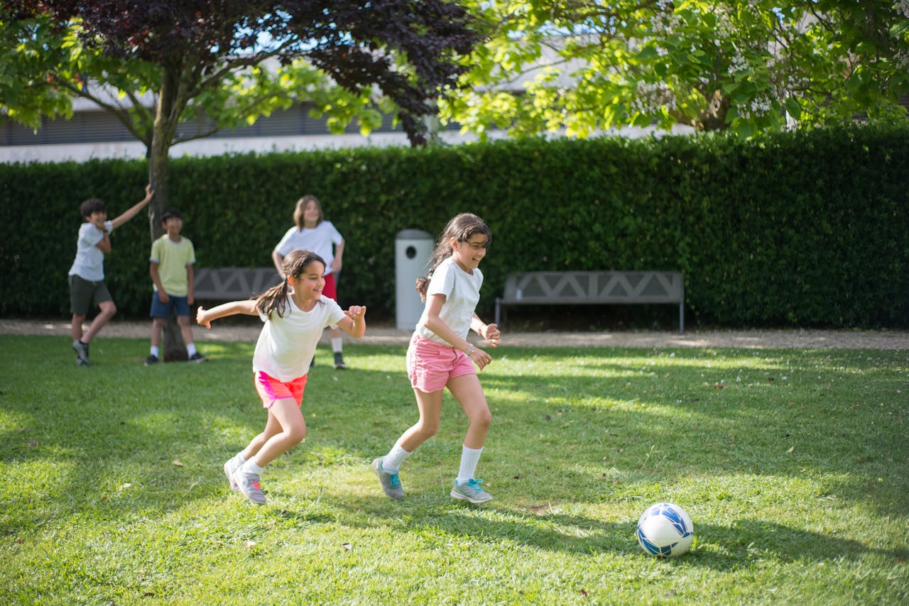 Children enjoy a game of soccer in a sunny park in Portugal, showcasing fun and leisure.